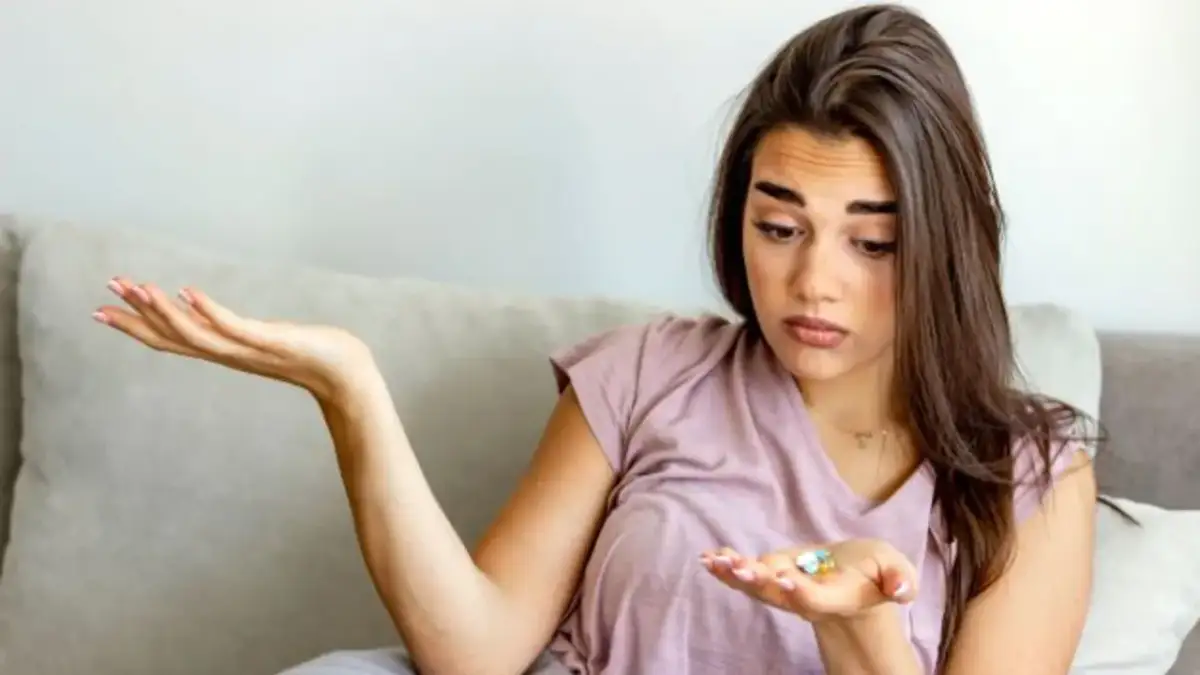 Zastanawiam się, jaki odstęp między antybiotykiem a ibuprofenem jest bezpieczny. Kobieta trzyma kilka tabletek na dłoni.