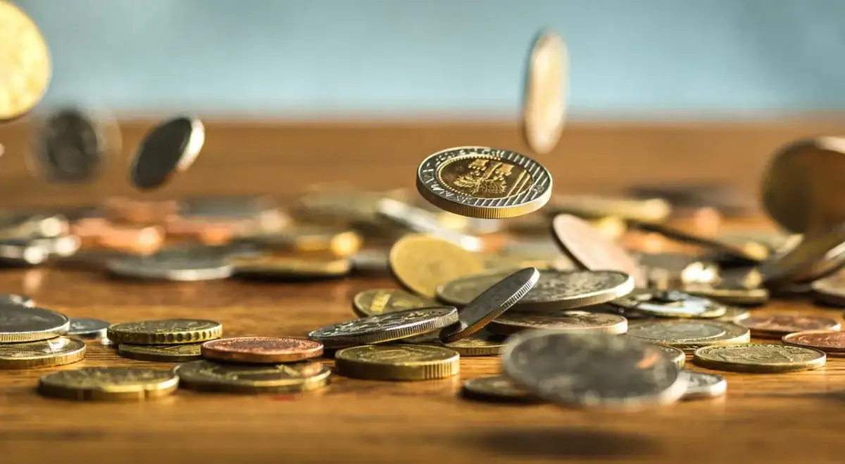 Monety spadają na drewniany blat. Zastanawiasz się, jak wyczyścić monety domowym sposobem? Oto kilka wskazówek.