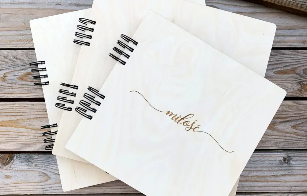 Drewniane notesy z napisem "miłość" na spirali, ułożone na drewnianym tle.