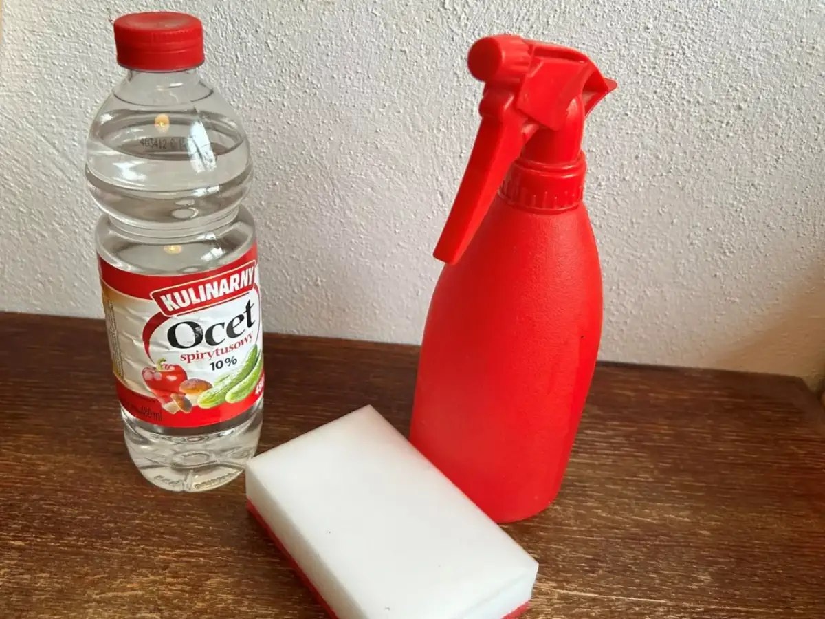 Butelka octu, czerwony spryskiwacz i gąbka do czyszczenia granitu octem.