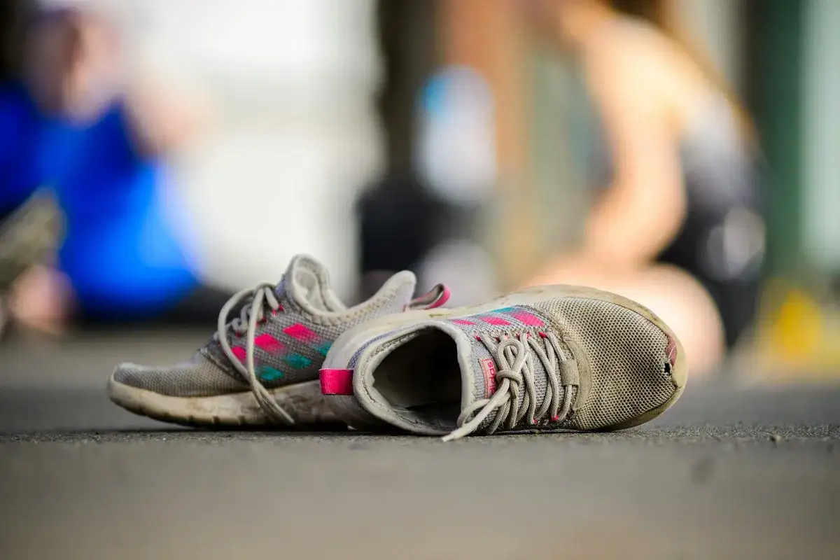 Para jak zaszyć dziurę w bucie na palcu, potrzebuje trochę pracy. Zniszczone buty sportowe leżą na ziemi, z widoczną dziurą w jednym z czubków.