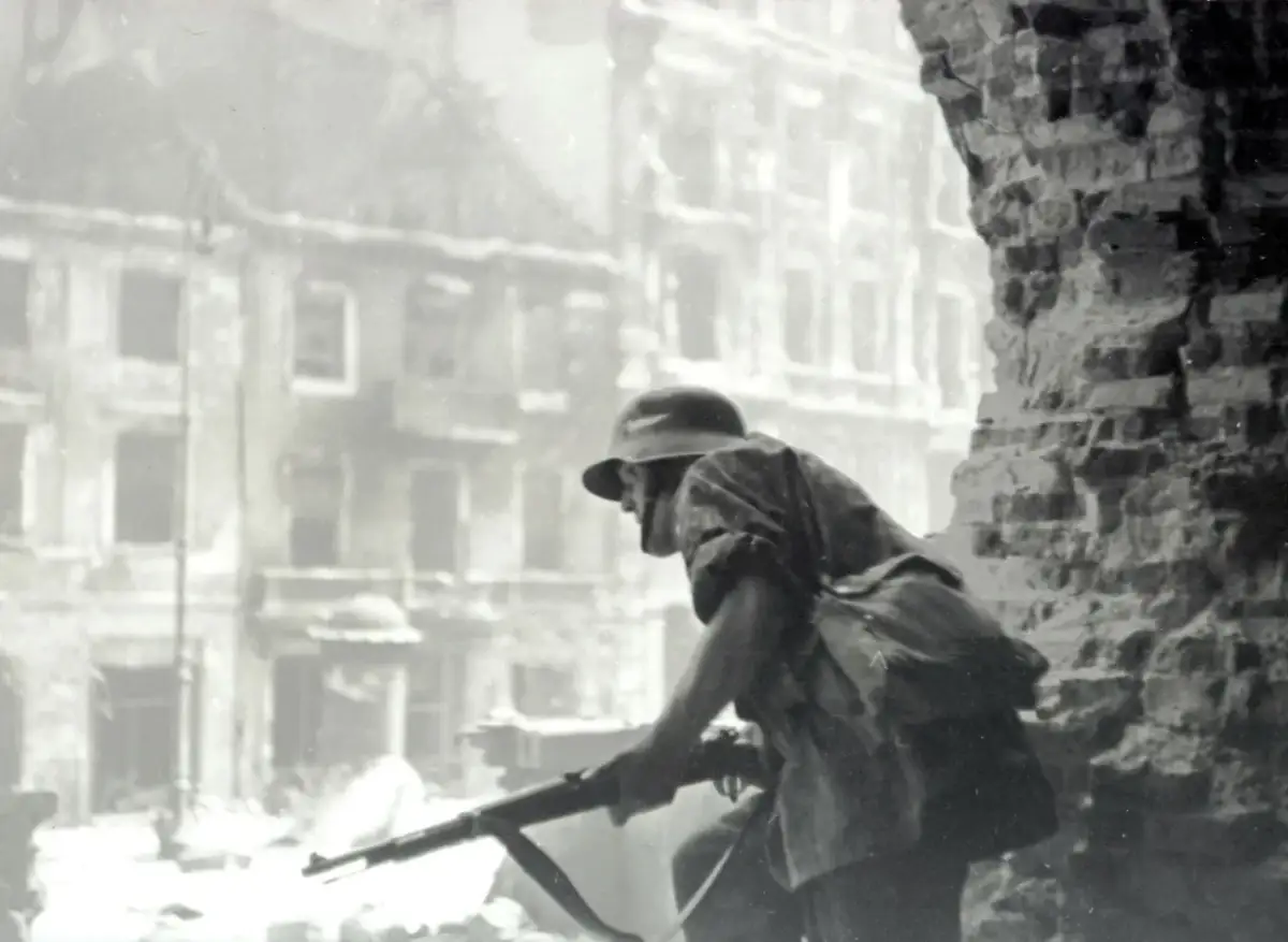 Żołnierz z karabinem w ruinach miasta. Czy powstanie warszawskie miało sens? Pytanie to wciąż budzi emocje.