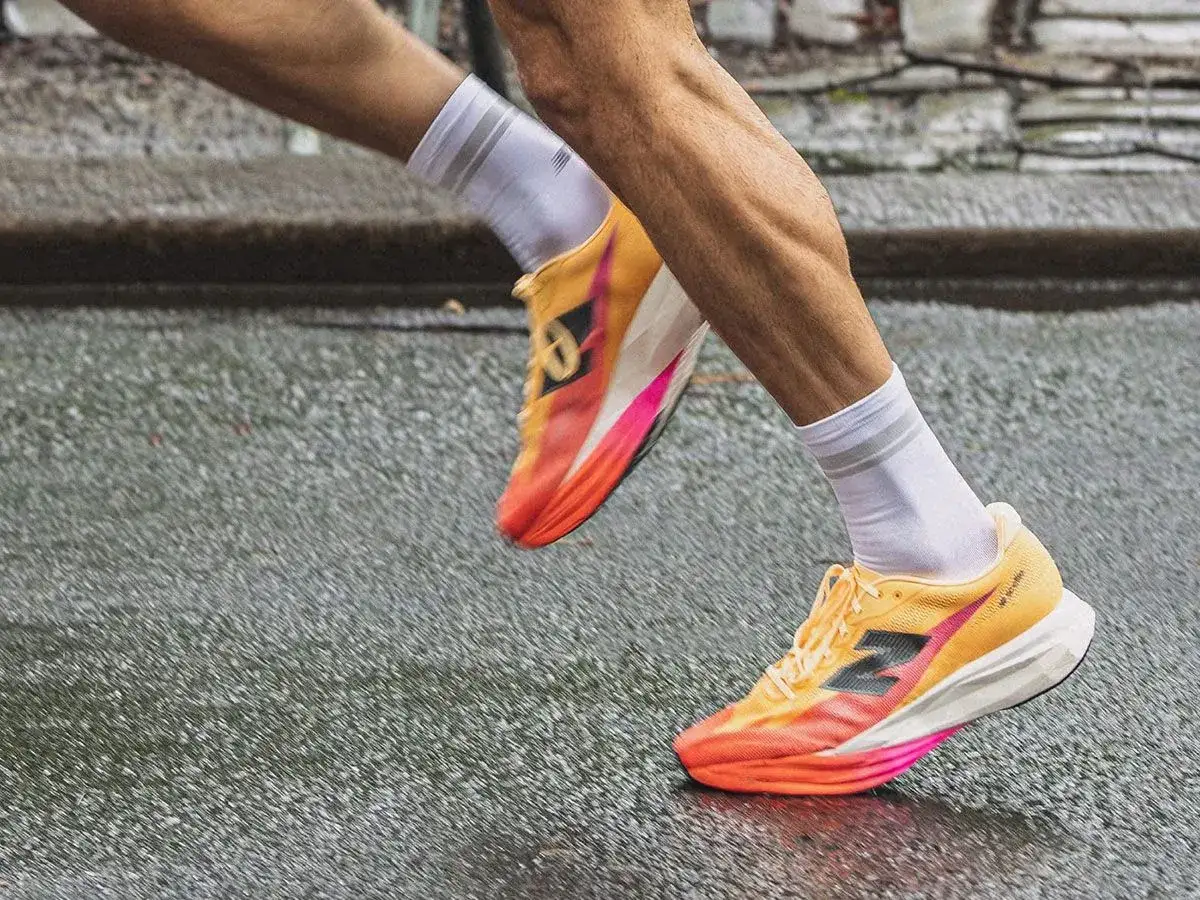 Biegacz w kolorowych butach do biegania, idealnych na treningi hiit, pokonuje mokrą nawierzchnię.