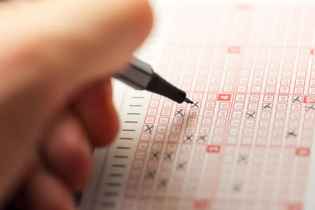 Ręka z długopisem zaznacza liczby na kuponie lotto, marząc o wygranej w jackpot.