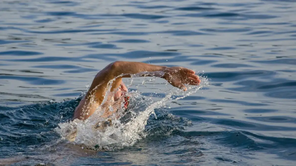 Pływak wykonuje szybki ruch ramieniem w stylu dowolnym, który jest najszybszy. Woda rozpryskuje się wokół jego głowy.