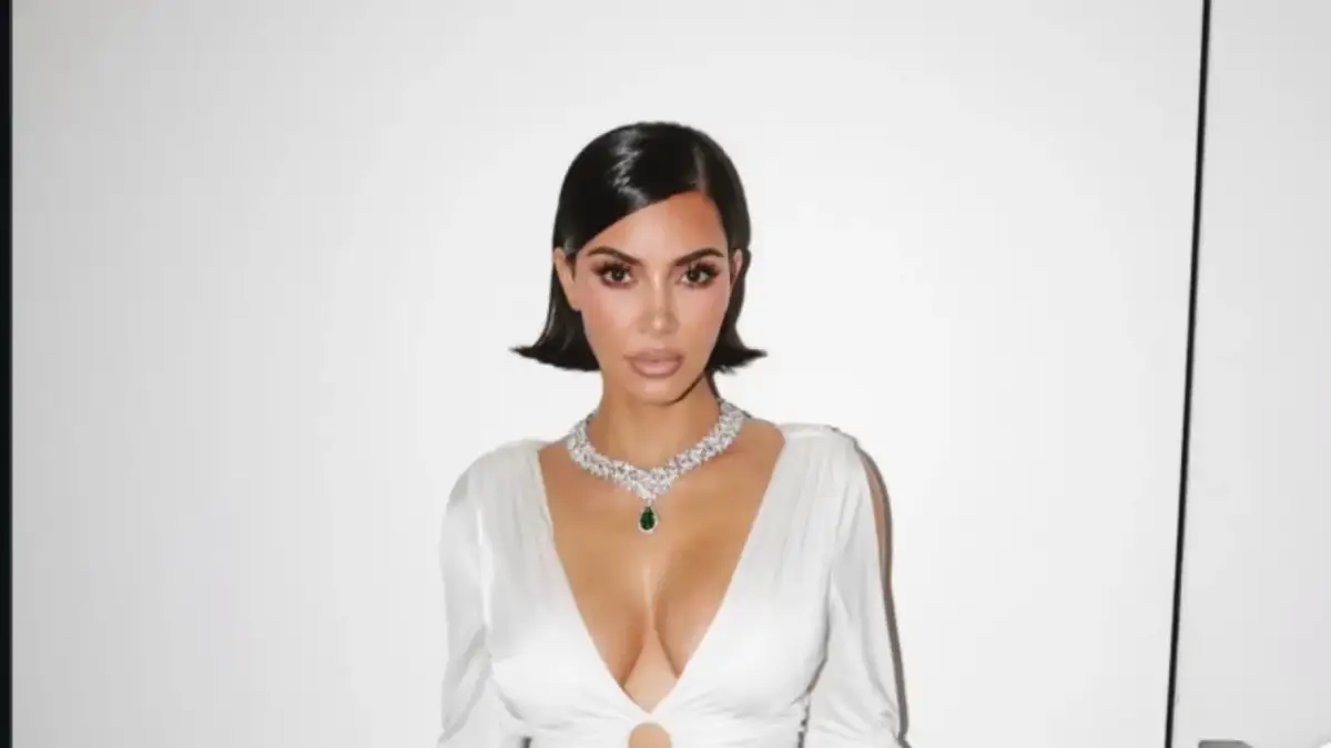 Kim Kardashian w białej sukni z głębokim dekoltem i naszyjnikiem z diamentów i szmaragdu.