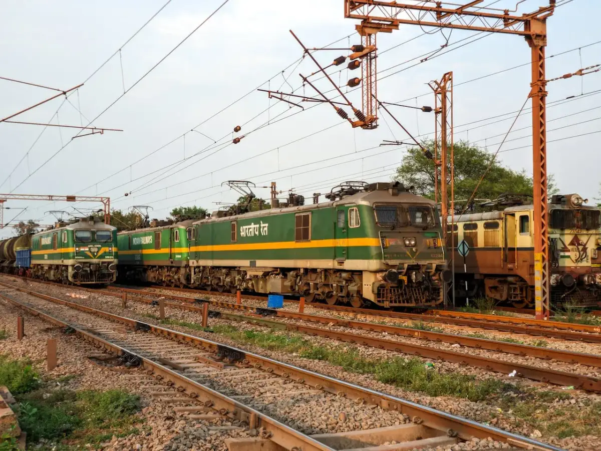 Zielone lokomotywy elektryczne stojące na torach kolejowych pod siecią trakcyjną.