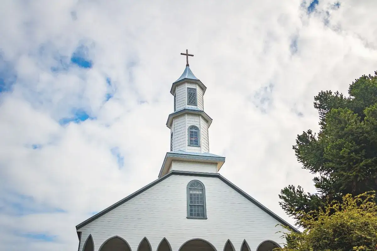 Biały kościół z krzyżem na wieży, pod błękitnym niebem. Planujesz ślub i zastanawiasz się, jak załatwić bierzmowanie przed ślubem?