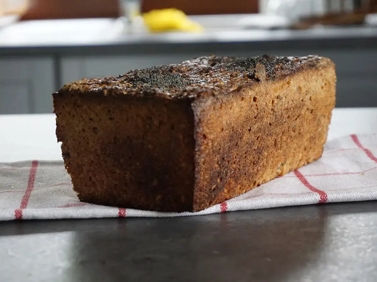 Bochenek ciemnego chleba żytniego z makiem na kuchennym blacie.