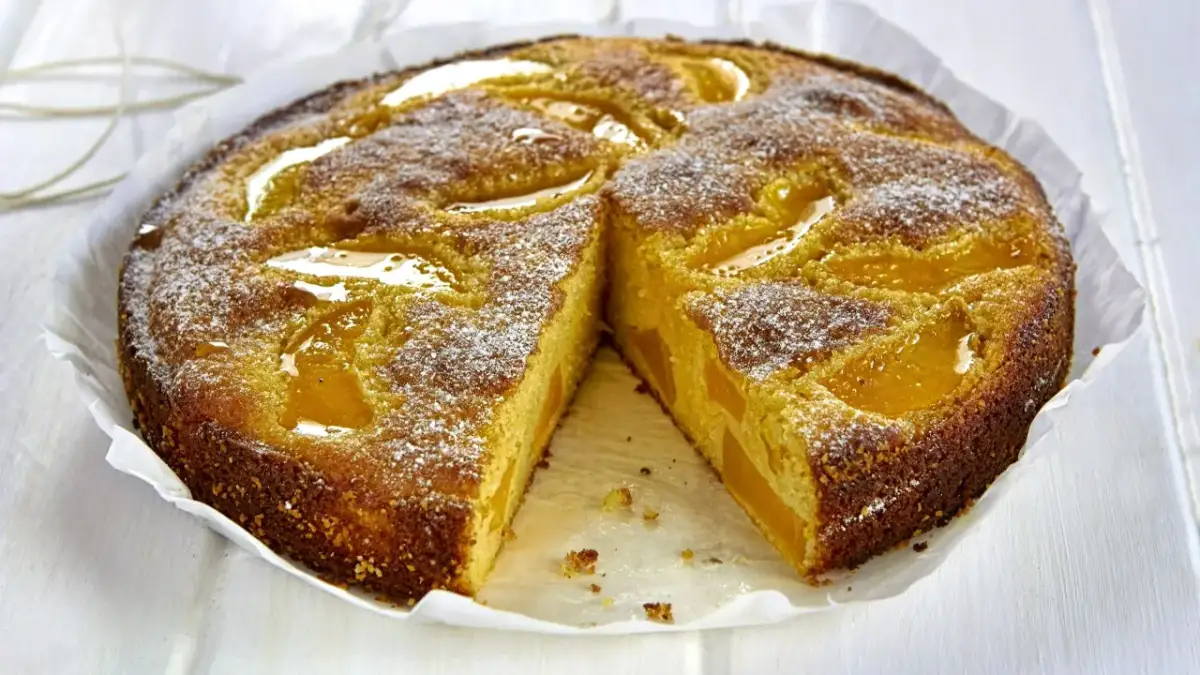 Pyszne ciasto z serem i brzoskwiniami, posypane cukrem pudrem. Idealne na deser.