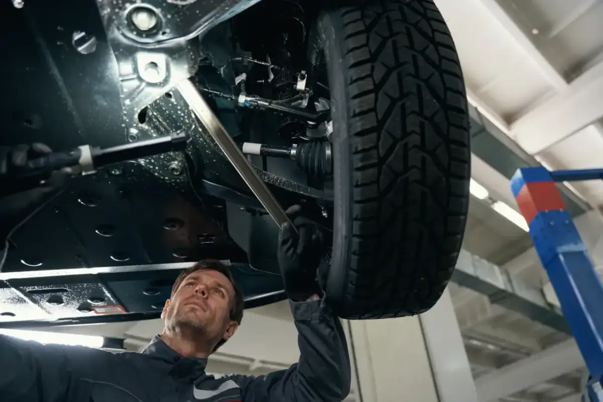 Mechanik bada podwozie samochodu, szukając przyczyny rytmicznego stukania podczas jazdy.