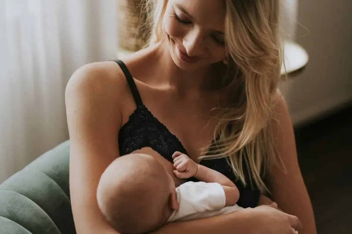 Uśmiechnięta mama karmi piersią swoje dziecko. Delikatne chwile bliskości i miłości.