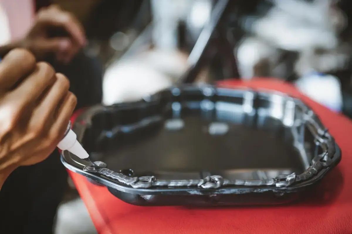 Aplikacja silikonu wysokotemperaturowego na miskę olejową. Czas schnięcia silikonu wysokotemperaturowego jest kluczowy dla szczelności.