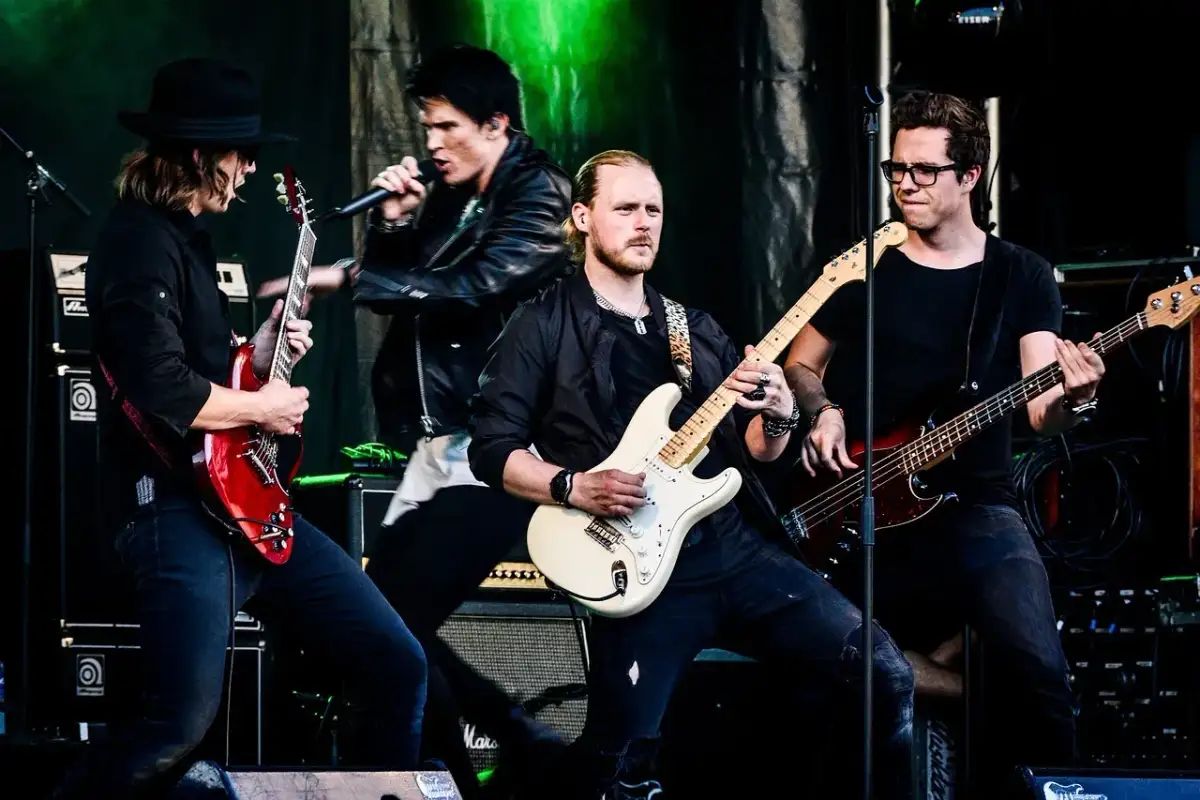 Zespół gra na scenie, wokalista śpiewa, gitarzyści i basista tworzą muzykę. Może to piosenka "Kocham Cię".