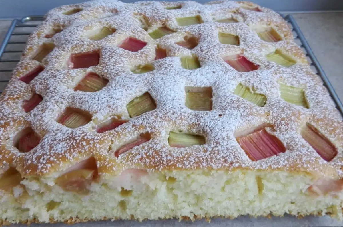 Puszyste ciasto jogurtowe z rabarbarem i kruszonką, posypane cukrem pudrem. Idealne na letnie popołudnie.