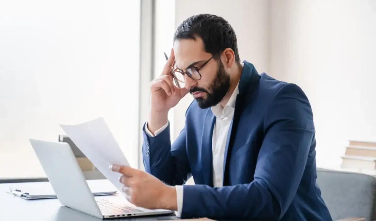 Mężczyzna w okularach analizuje dokumenty, myśląc o wykreśleniu z BIK po spłacie.