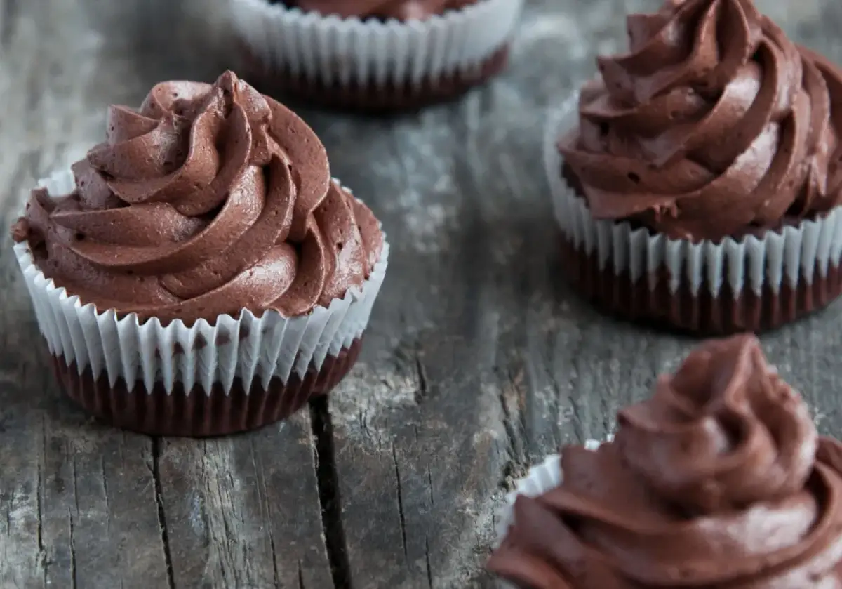 Kilka pysznych muffinek z kremem czekoladowym, ułożonych na drewnianym blacie.