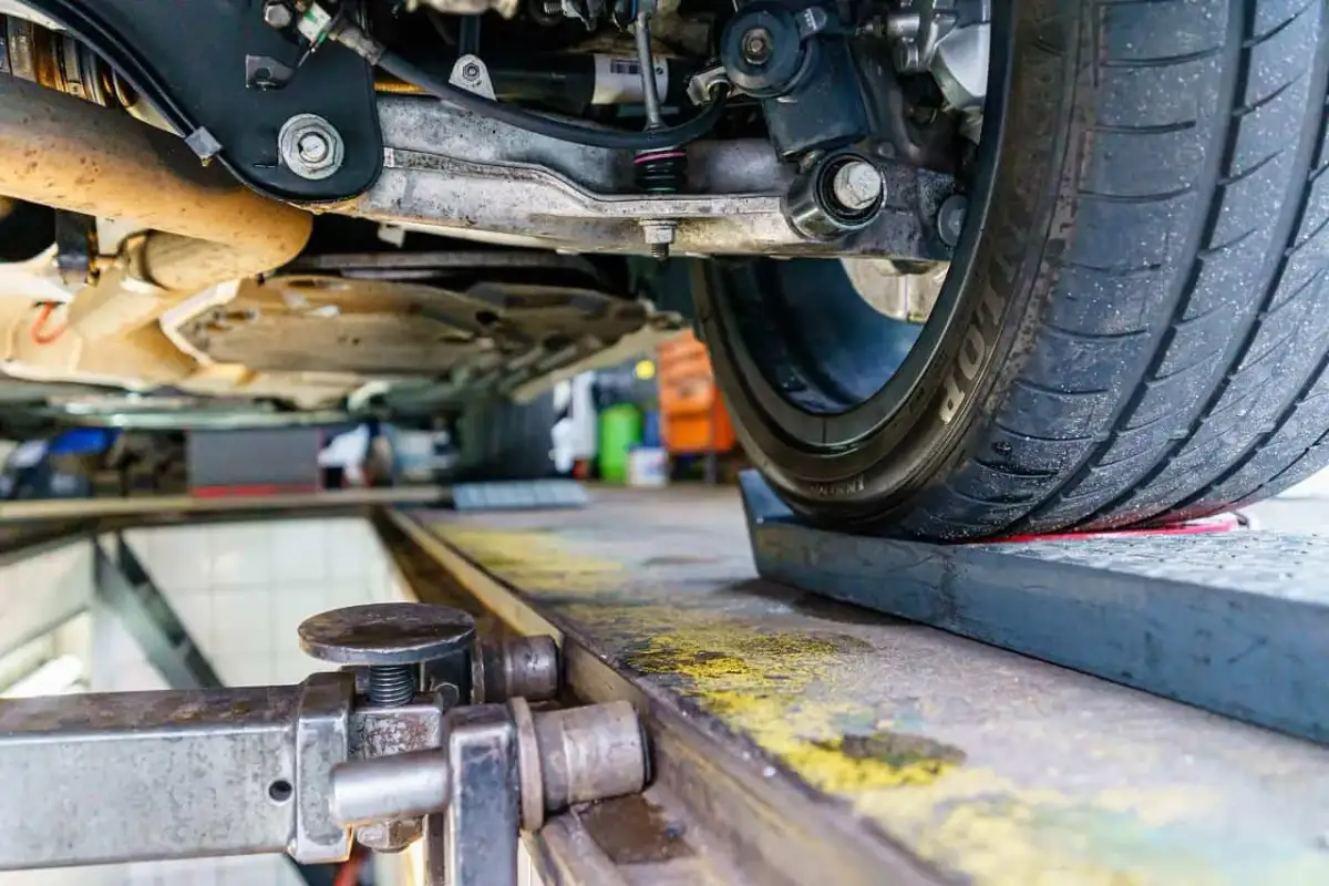 Podnośnik samochodowy i koło na podnośniku, przygotowanie do tego, jak samemu ustawić zbieżność.