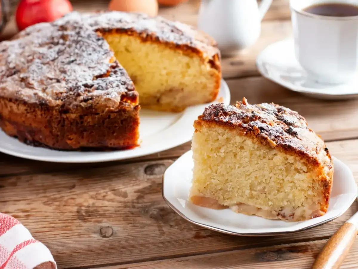 Pyszny jabłecznik na biszkopcie, posypany cukrem pudrem, czeka na kawę.