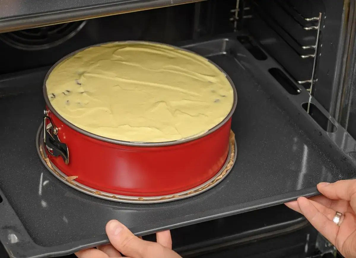 Sernik w czerwonej tortownicy wkładany do piekarnika. Czy sernik może zostać na noc w piekarniku? Lepiej nie ryzykować!