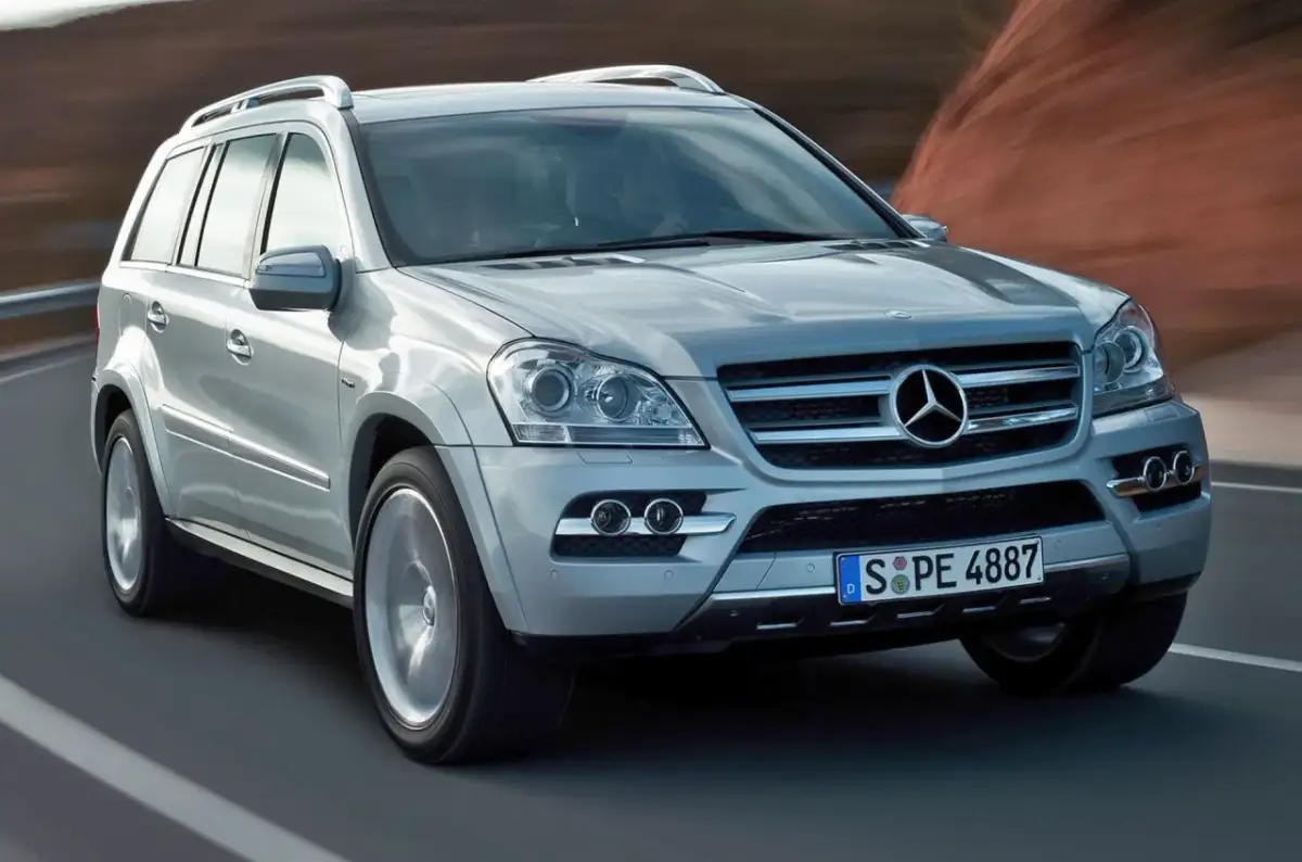 Srebrny Mercedes-Benz GL Class pędzi po drodze, za nim rozmyte krajobrazy.