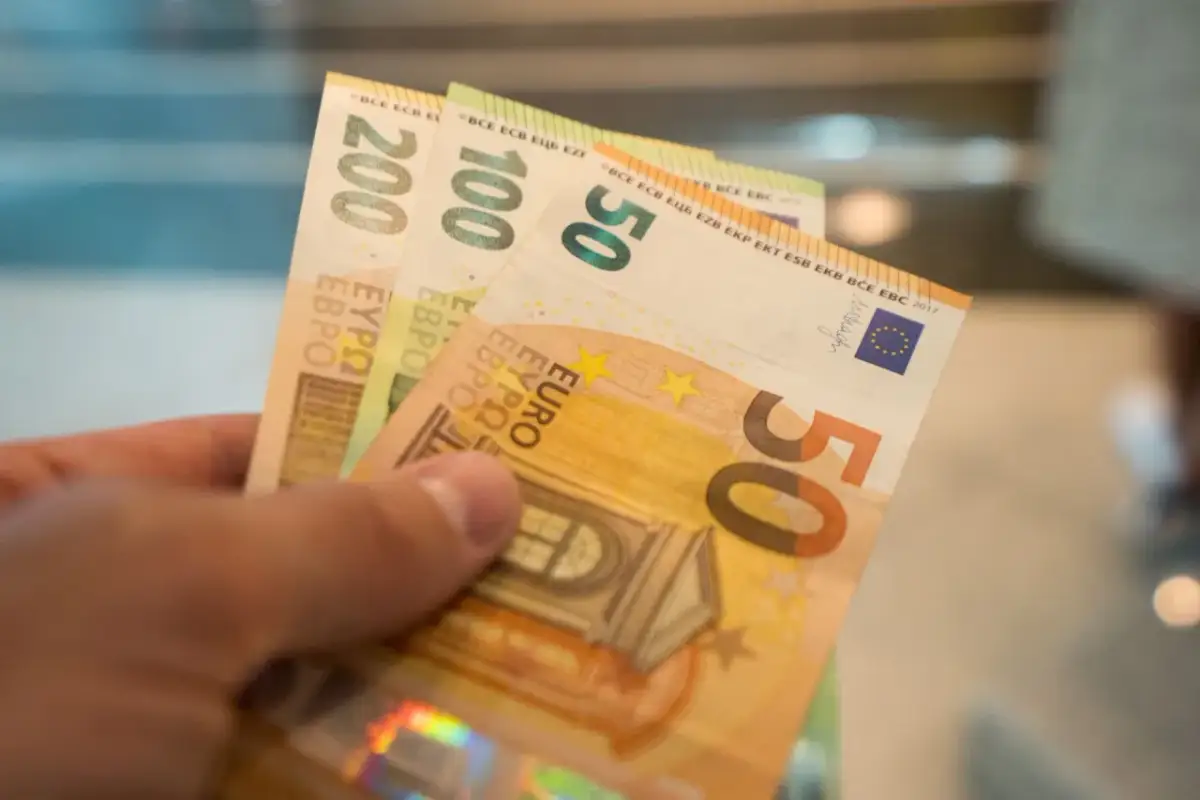 Dłoń trzyma banknoty 50, 100 i 200 euro. Od 2015 roku jaka waluta na Litwie to euro.