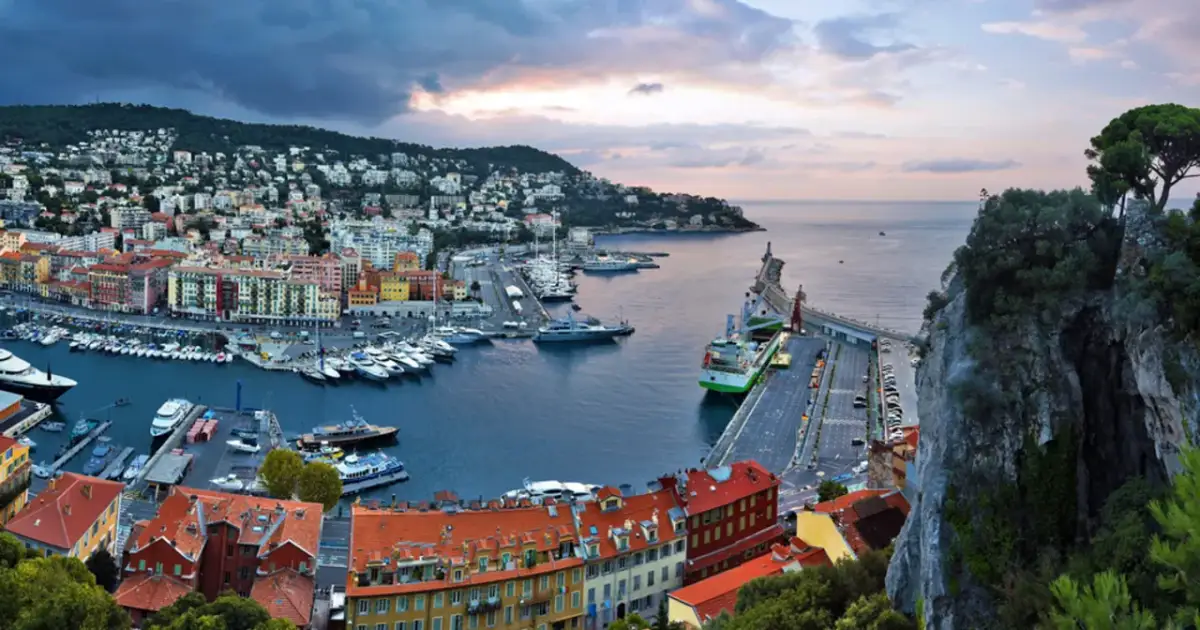 Widok na port w Nicei, gdzie cumują jachty. W tle kolorowe kamienice i wzgórza. We Francji obowiązuje euro, więc za zakupy zapłacisz w tej walucie.