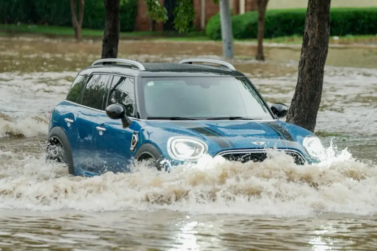 Niebieski Mini Cooper przedziera się przez powódź. Ubezpieczenie GAP przy zakupie za gotówkę chroni przed stratami w takich sytuacjach.