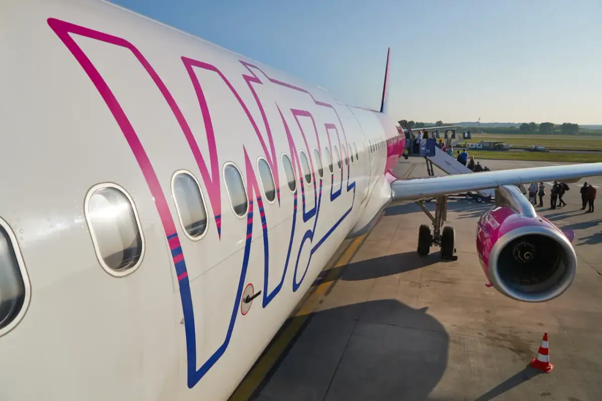 Samolot Wizz Air z widocznym logo, pasażerowie wsiadają po schodkach.