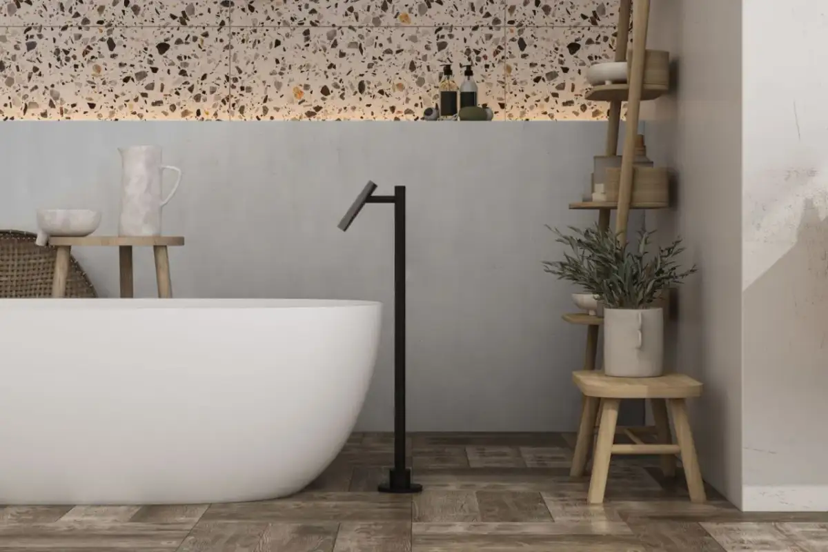Nowoczesna łazienka z wanną, czarną baterią stojącą i półkami z rośliną.