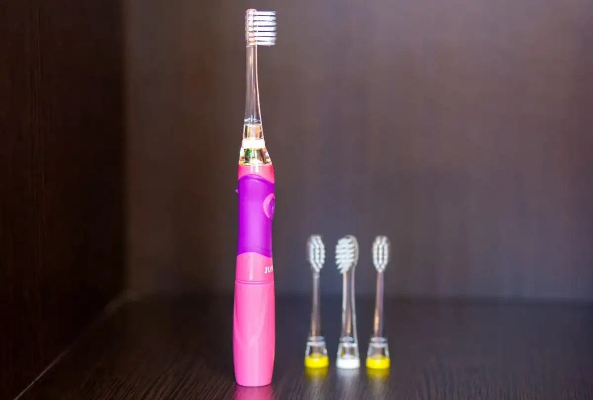 Różowa szczoteczka soniczna dla dzieci z trzema zapasowymi końcówkami.