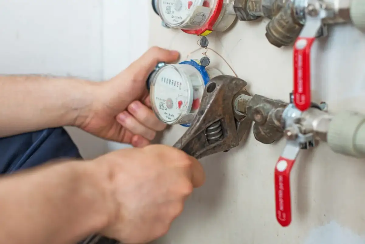 Instalator dokręca kluczem wodomierz, który wymaga wymiany. Sprawdź, co ile wymienia się wodomierze, by uniknąć problemów.