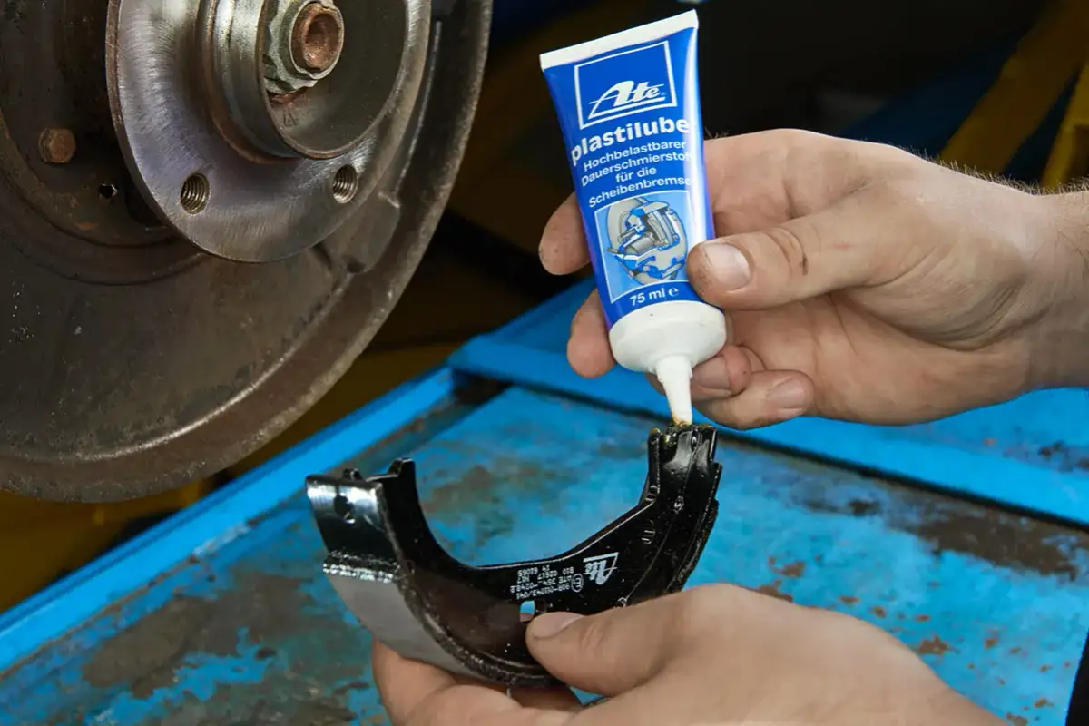 Mechanik aplikuje smar ATE Plastilube na prowadnice szczęki hamulcowej, dbając o prawidłowe działanie układu hamulcowego.