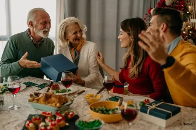 Rodzina przy świątecznym stole cieszy się wspólnym czasem, wręczając sobie prezenty, otoczona smacznymi potrawami i dekoracjami w bożonarodzeniowym klimacie