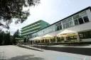 Tanie sanatorium prywatnie: zielony budynek z balkonami i tarasem z parasolami Tyskie.