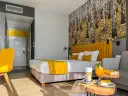 Pokój hotelowy z motywem lasu, żółtym akcentem i napojami. Idealne miejsce na relaks, jak sugerują notera hotel spa opinie.
