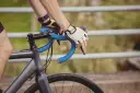 Rowerzysta w rękawiczkach trzyma kierownicę, zbliżając się do swojego progu mleczanowego.