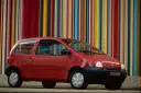 Renault Twingo 1 rouge devant un mur de bandes colorées verticales.