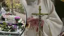 Parafianin w białej szacie trzyma hostię i krzyż. Obok cmentarz z kwiatami i zniczami.