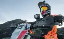 Motocyklista w kasku z kamerą na kierownicy, gotowy do jazdy po górskim terenie. Idealna kamera na kask motocyklowy do uchwycenia przygody.