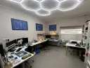 Werkstatt für Smartphone- und MacBook-Reparatur mit Werkzeugen, Mikroskop und technischen Zeichnungen.