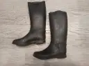 Para czarnych gumowych kaloszy jeździeckich na jasnym, drewnianym tle.