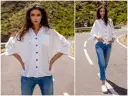Modelka prezentuje, jak nosić koszulę damską do spodni. Biała, luźna koszula i jeansy tworzą stylowy, casualowy look.