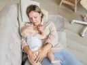 Mama karmi dziecko spod pachy na kanapie. Ciepła chwila bliskości i spokoju.