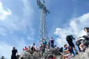 Tłum ludzi na skalistym szczycie podziwia imponującą wysokość krzyża na Giewoncie.