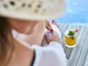 Relaks przy basenie z drinkiem w hotelu dla dorosłych Polska. Kobieta w słomkowym kapeluszu odpoczywa na leżaku.