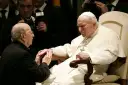 Papież Jan Paweł II w białej szacie, klęczący mężczyzna w czerni. W tle widać fotografów. To obraz duchowej siły, jakiej doświadczają legiony Chrystusa.
