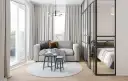 Jasna, nowoczesna kawalerka z wydzieloną sypialnią za szklaną ścianką. W salonie sofa, stoliki i okrągły dywan.