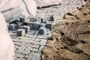 Kupa kostki brukowej i piasku, gotowe do ułożenia. Widać worki z materiałem i przygotowany podkład, czyli ile podsypki pod kostkę potrzeba.