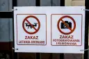 Dwa znaki na płocie: zakaz latania dronami i zakaz fotografowania i filmowania.